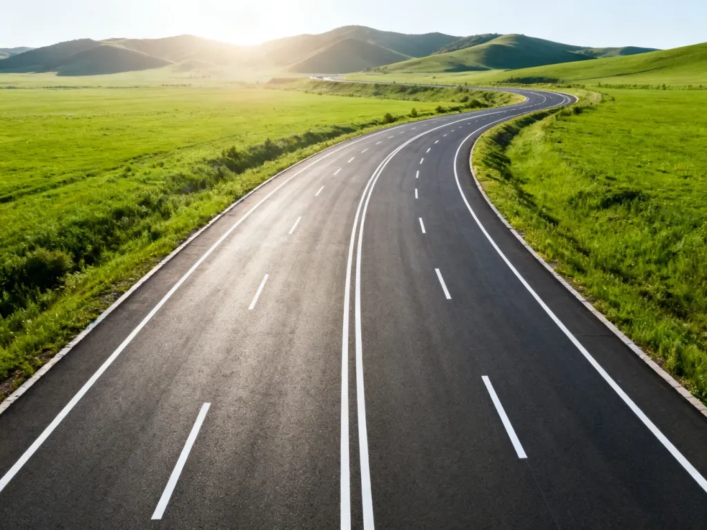 Nowoczesna, wielopasmowa autostrada biegnąca przez zielony krajobraz, ilustrująca rozwój infrastruktury drogowej w Polsce.